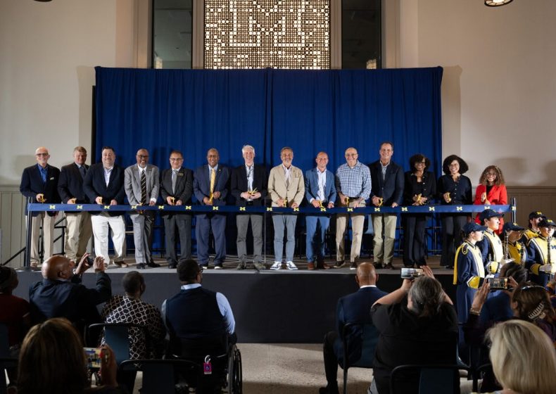 University of Michigan and American Campus Communities representatives prepare to cut the ceremonial ribbon at Wolverine Village, marking the opening of the more than $600 million student housing development.