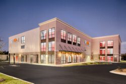 Dusk exterior shot labeled “Pooler Night” shown as a commercial retail property example tied to Madison Capital Group’s launch of the $200M Car Wash & Convenience Opportunity Fund, illustrating the type of brick-and-mortar retail/convenience assets the fund targets.