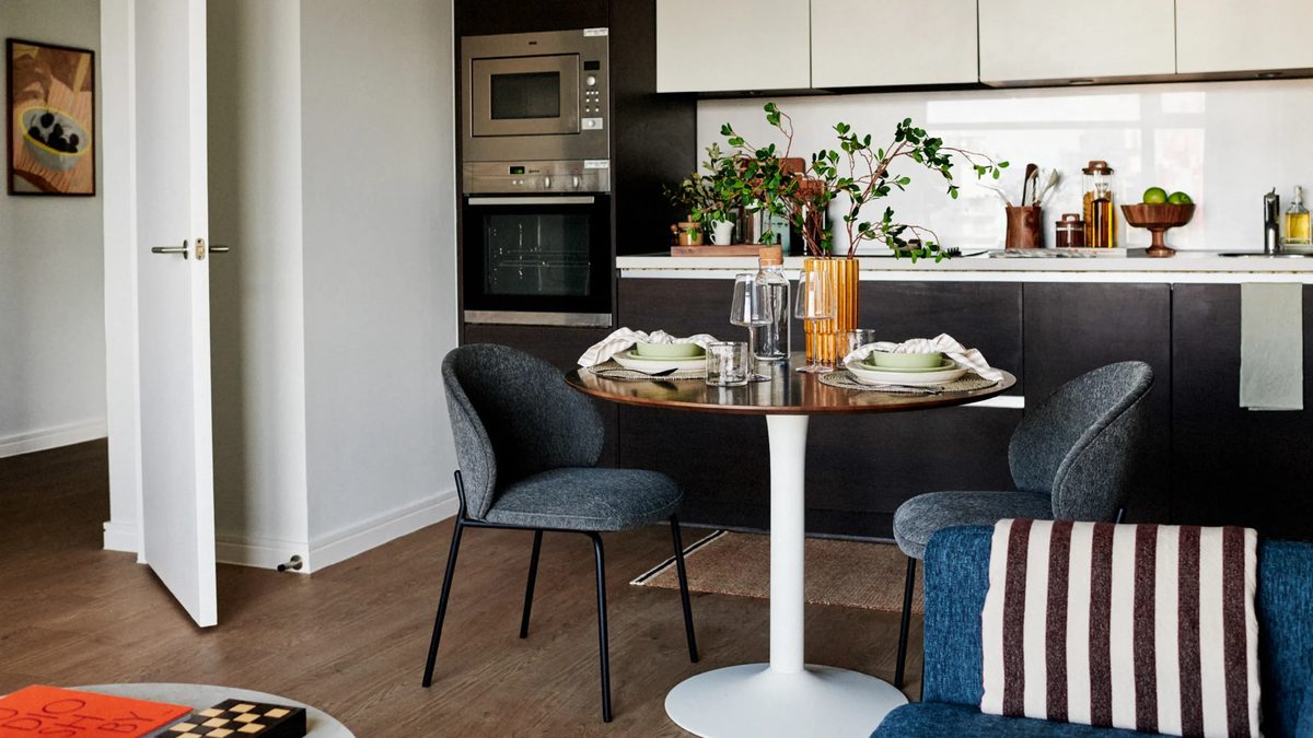 A staged modern kitchen and dining nook representative of the UNCLE build-to-rent apartment interiors tied to QuadReal’s £120M forward-funded Woolwich development, illustrating the type of unit finishes the 241-unit project will deliver.
