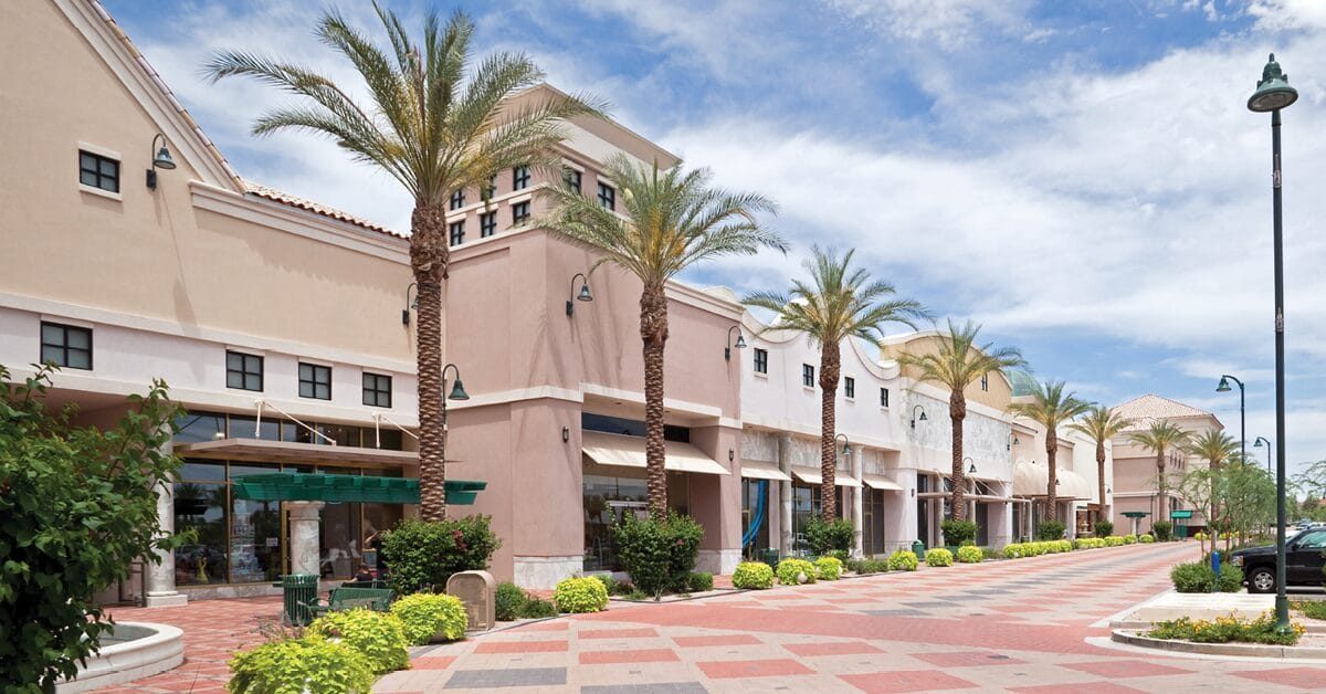 Outdoor neighborhood retail center framed by palm trees, representative of the suburban retail inventory that CoStar, cited by Voit Real Estate Services, says is experiencing historically low vacancy and constrained new supply in 2026.