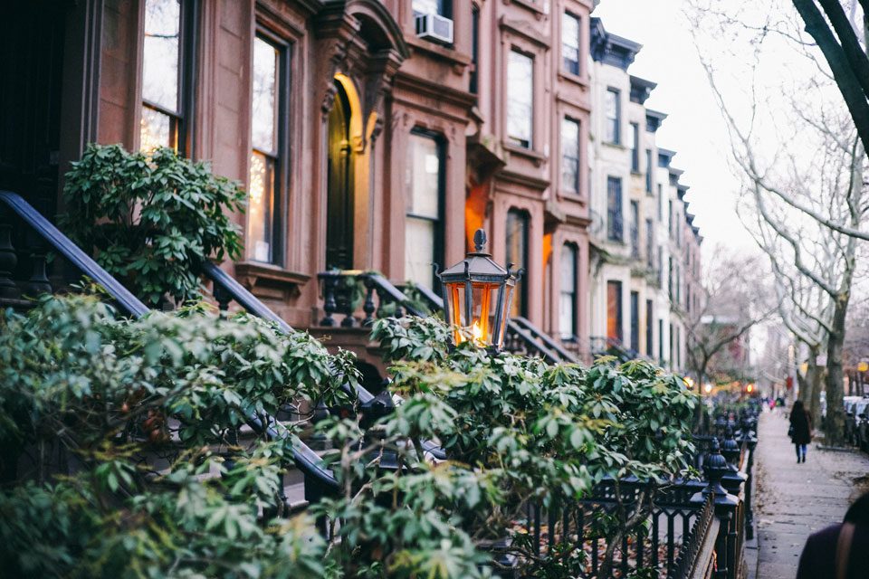 A row of New York brownstones and stoops illustrating the type of condominium inventory Urban Standard Capital plans to acquire with its $100M fund to help sponsors meet conversion sales thresholds and rent unsold units for cash flow.